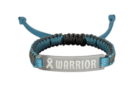 A bracelet with teal and black micro cord and an engraved metal tag that reads Warrior with a ribbon symbol displayed on a plain white background.